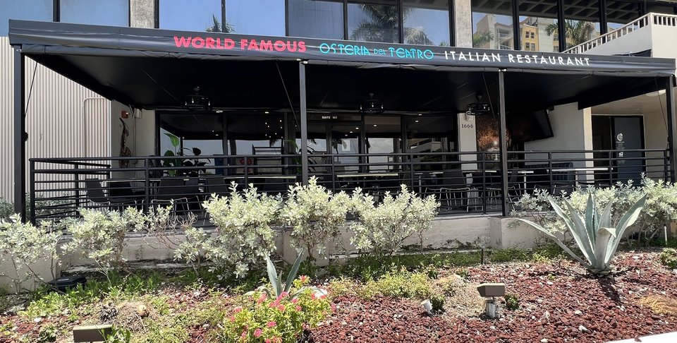 Italian restaurant exterior with porch seating and signage.